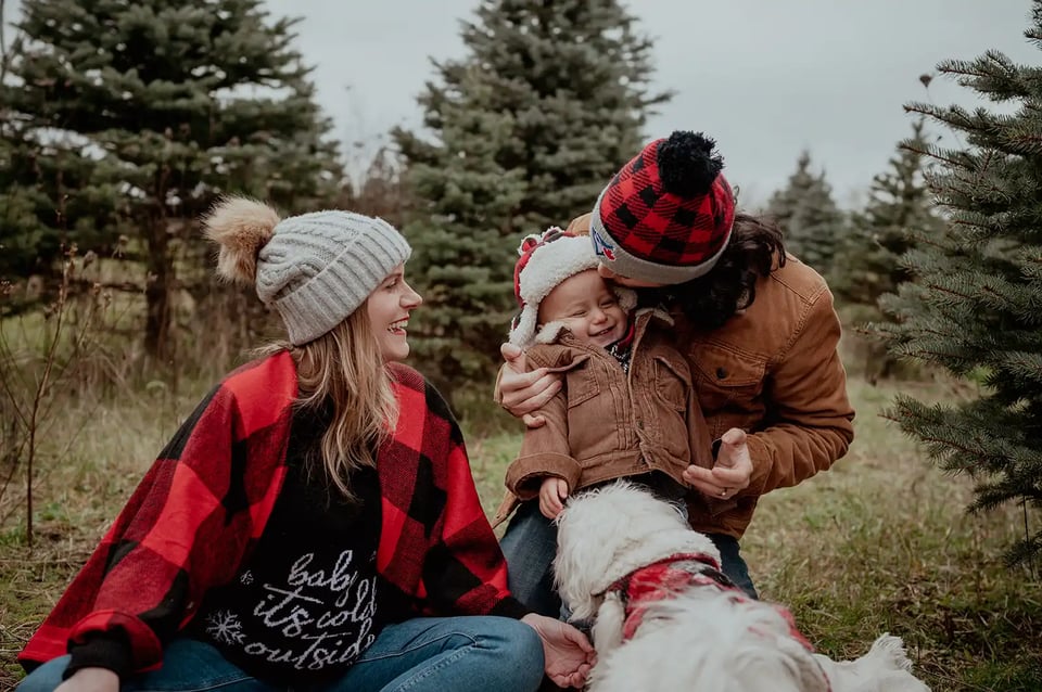 Parents laughing with their child in pine tree field