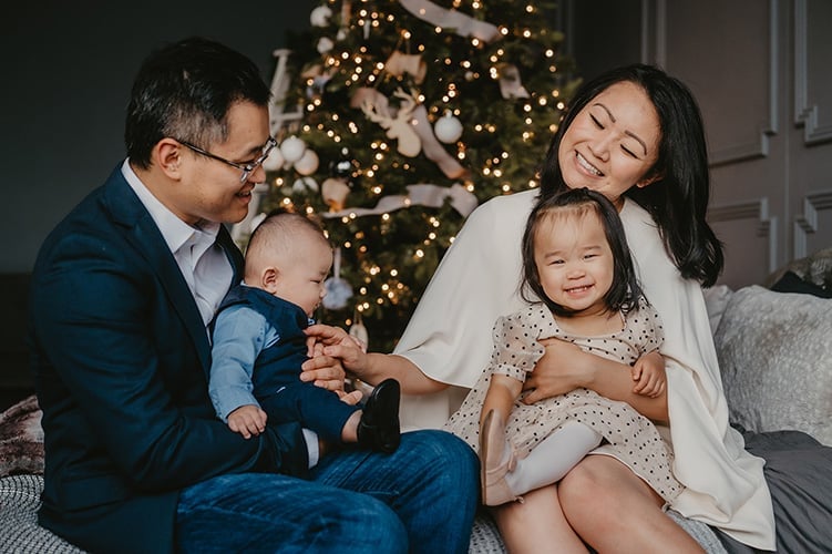 Family of four sharing a moment beside a Christmas tree