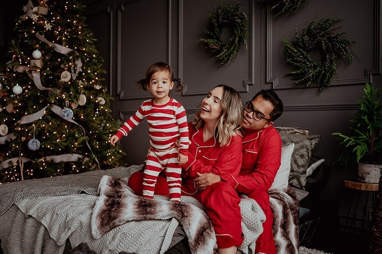 Family in red holiday pyjamas beside a Christmas tree